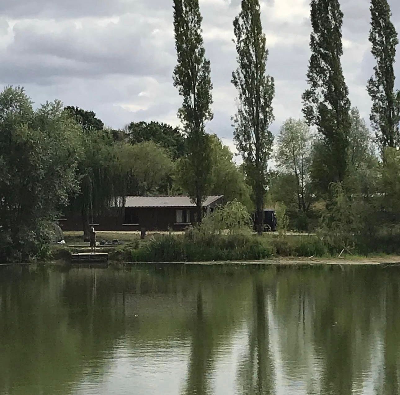 Hidden carp fishing lake surrounded by trees and calm water